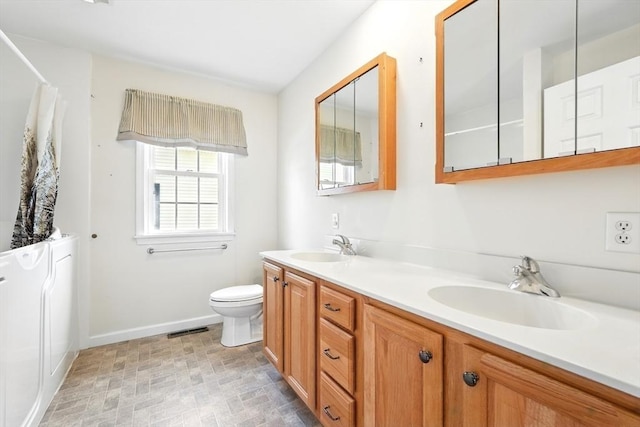 bathroom featuring double vanity, toilet, visible vents, and a sink