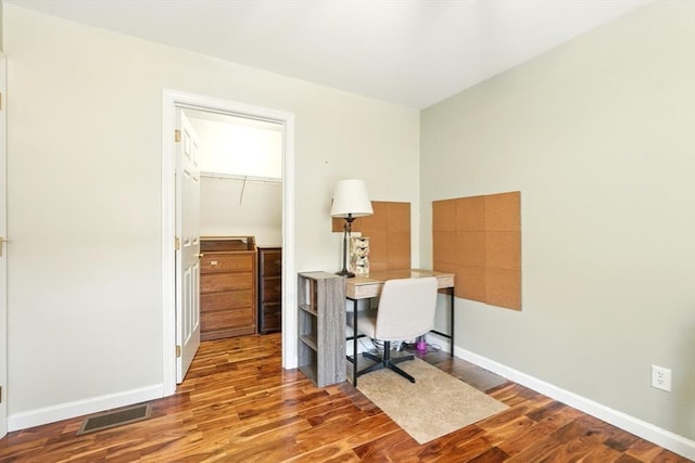 office space featuring wood finished floors, visible vents, and baseboards