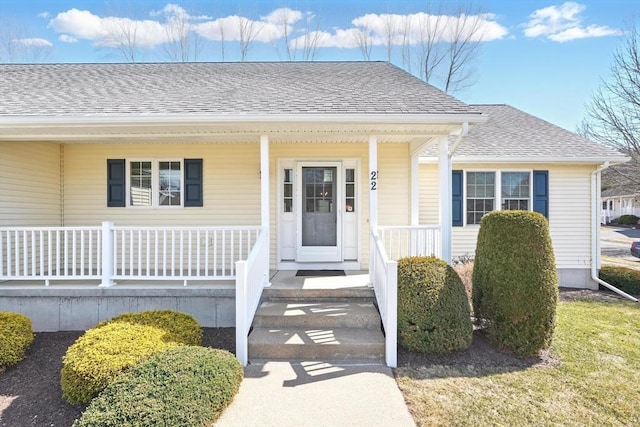 entrance to property featuring a porch and a shingled roof