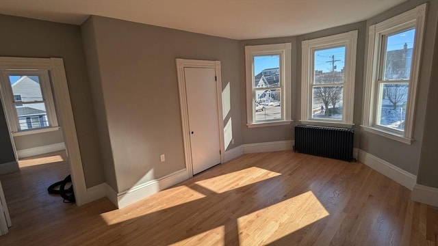 unfurnished bedroom with radiator, baseboards, and wood finished floors