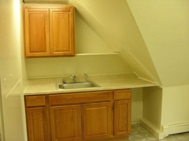 kitchen with brown cabinets, a baseboard radiator, light countertops, and a sink