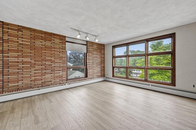 466 Hosmer St, Marlborough, MA 01752 - spare room with rail lighting, brick wall, wood finished floors, and a baseboard radiator