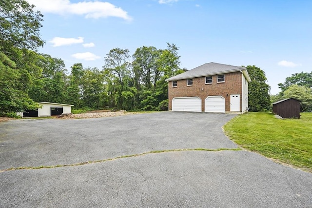 466 Hosmer St, Marlborough, MA 01752 - view of property exterior with brick siding, asphalt driveway, a lawn, a garage, and an outbuilding