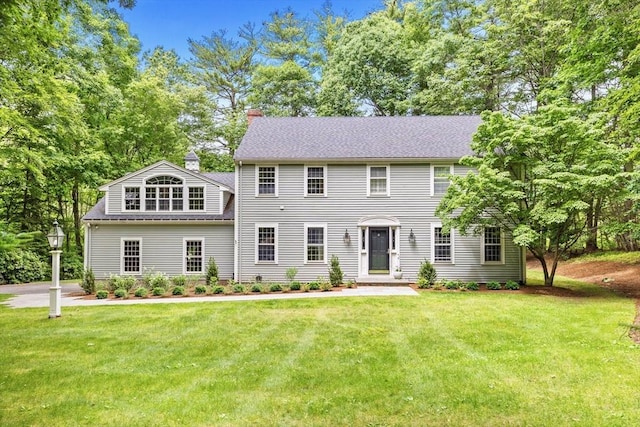 colonial home with a chimney and a front lawn