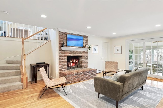 living area featuring recessed lighting, a fireplace, wood finished floors, stairs, and ornamental molding