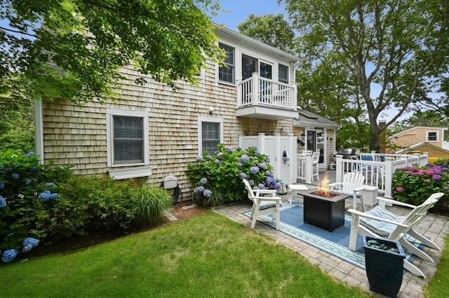 rear view of house with a yard, an outdoor fire pit, a patio area, and a balcony