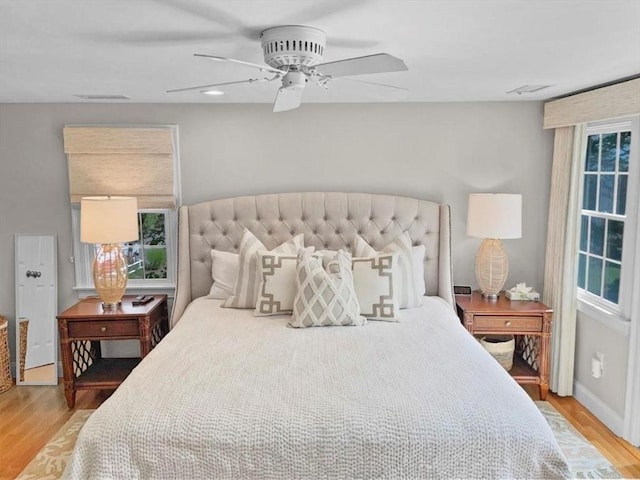 bedroom featuring ceiling fan, wood finished floors, visible vents, and baseboards