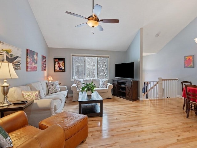 living room with light hardwood / wood-style floors, ceiling fan, and vaulted ceiling