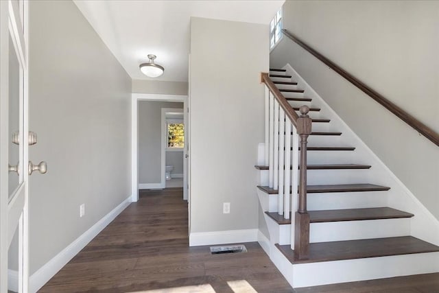 stairway featuring visible vents, baseboards, and wood finished floors