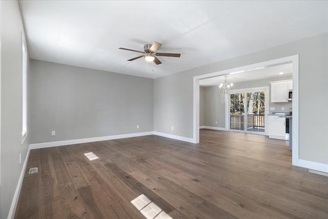 unfurnished room with ceiling fan with notable chandelier, dark wood finished floors, visible vents, and baseboards