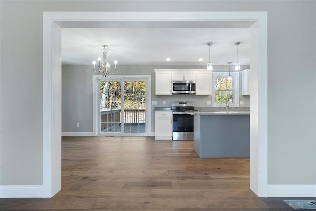 kitchen featuring baseboards, appliances with stainless steel finishes, dark wood-type flooring, white cabinetry, and pendant lighting