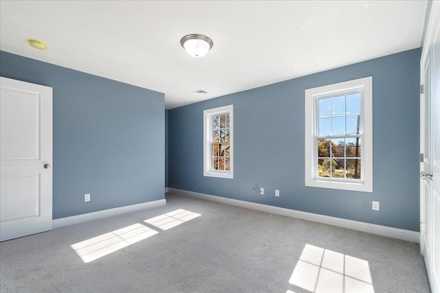 carpeted empty room featuring visible vents and baseboards