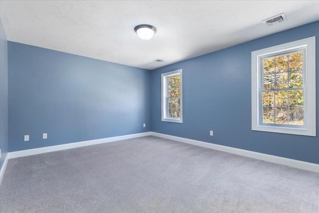 unfurnished room with carpet flooring, visible vents, and baseboards