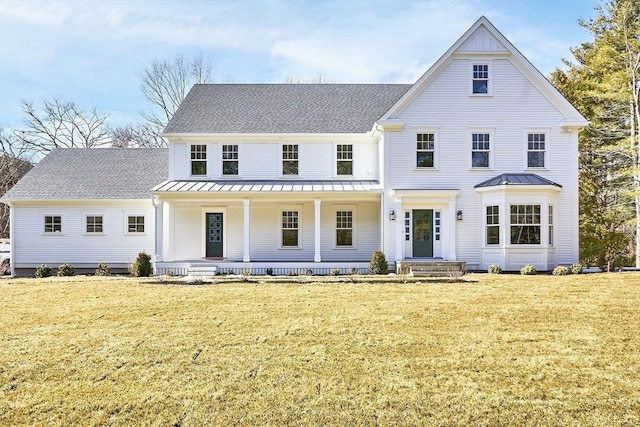 view of front facade with roof with shingles, a porch, a standing seam roof, metal roof, and a front lawn