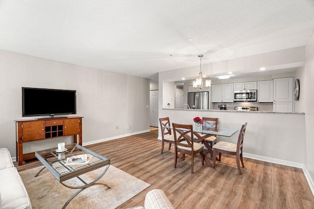 living area with baseboards, light wood finished floors, and a chandelier