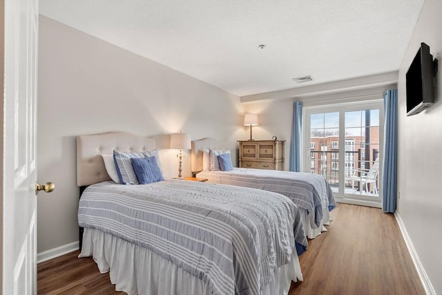 bedroom featuring access to exterior, visible vents, baseboards, and wood finished floors