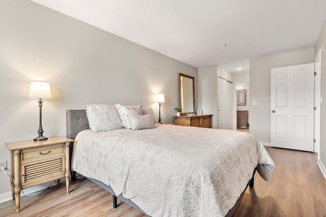 bedroom with a closet, light wood-style floors, baseboards, and ensuite bathroom