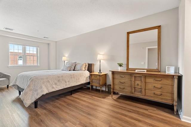 bedroom featuring wood finished floors and visible vents