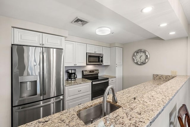 kitchen with visible vents, a sink, stainless steel appliances, white cabinetry, and tasteful backsplash