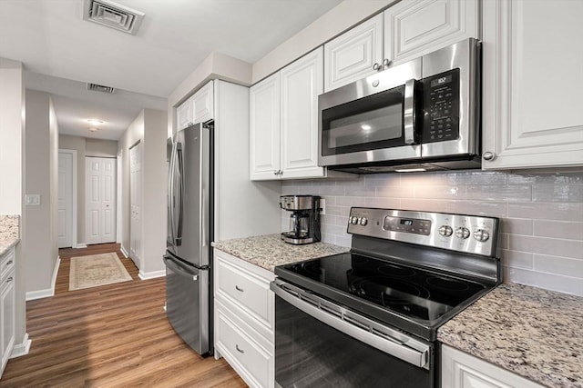 kitchen featuring light wood-type flooring, visible vents, appliances with stainless steel finishes, and white cabinetry