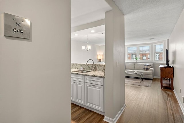 hall with a sink, a chandelier, baseboards, and wood finished floors