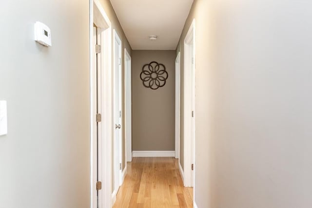 corridor featuring baseboards and light wood-style floors