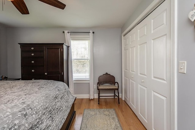 bedroom featuring light wood-style floors, baseboards, ceiling fan, and a closet