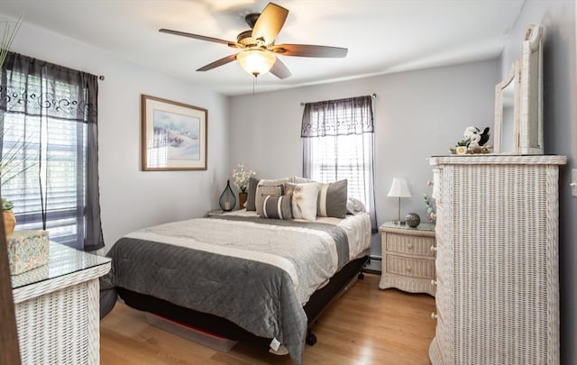 bedroom with a ceiling fan, wood finished floors, and baseboard heating