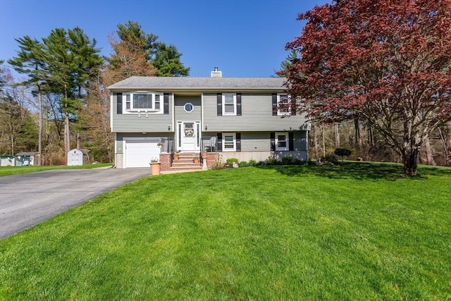 bi-level home featuring a garage, driveway, a chimney, and a front lawn