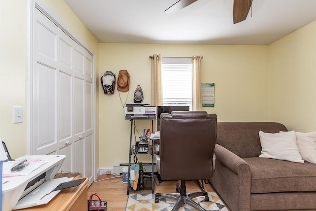office space featuring a ceiling fan, a baseboard radiator, and light wood-style floors