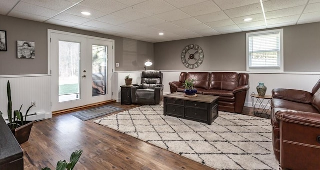 living room featuring a wainscoted wall, french doors, a drop ceiling, and wood finished floors