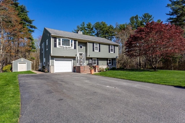 raised ranch featuring a chimney, an outbuilding, a garage, aphalt driveway, and a front lawn