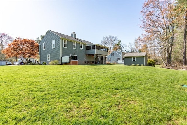 back of property with a sunroom, a chimney, and a yard