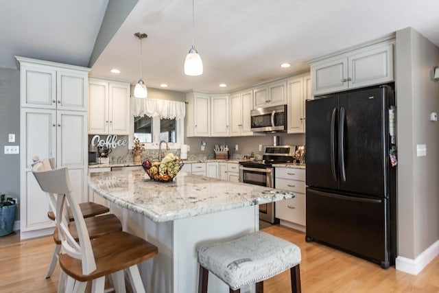 kitchen with stainless steel appliances, light wood-style floors, recessed lighting, and a kitchen bar