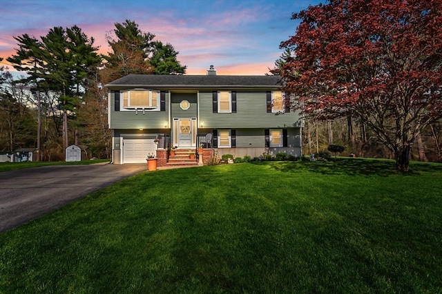 split foyer home featuring a lawn, a chimney, driveway, and a garage