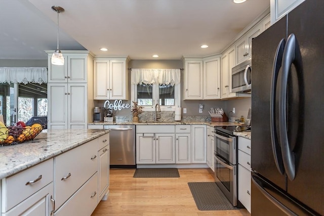 kitchen featuring recessed lighting, a sink, appliances with stainless steel finishes, and hanging light fixtures