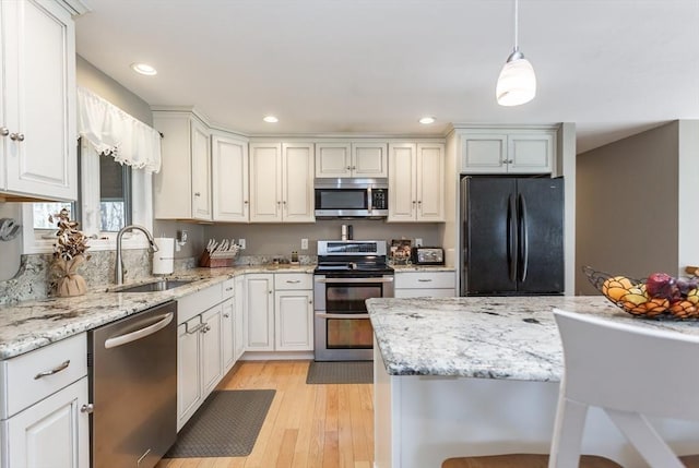 kitchen featuring light wood-type flooring, recessed lighting, a sink, decorative light fixtures, and stainless steel appliances