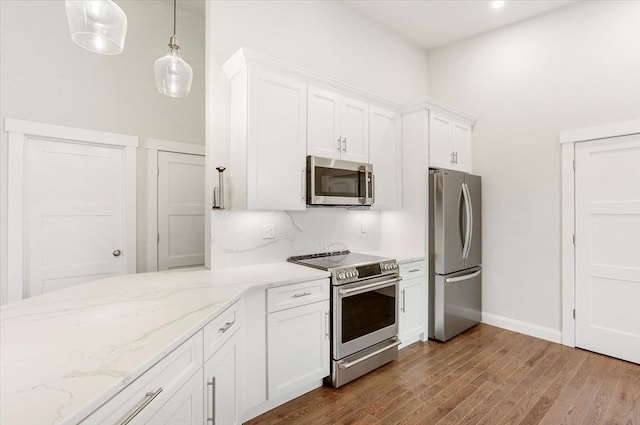 28 Main St Unit 4, Medford, MA 02155 - kitchen featuring stainless steel appliances, white cabinetry, dark wood finished floors, light stone counters, and hanging light fixtures
