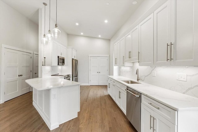 28 Main St Unit 4, Medford, MA 02155 - kitchen with stainless steel appliances, a sink, white cabinets, light wood-type flooring, and light stone countertops