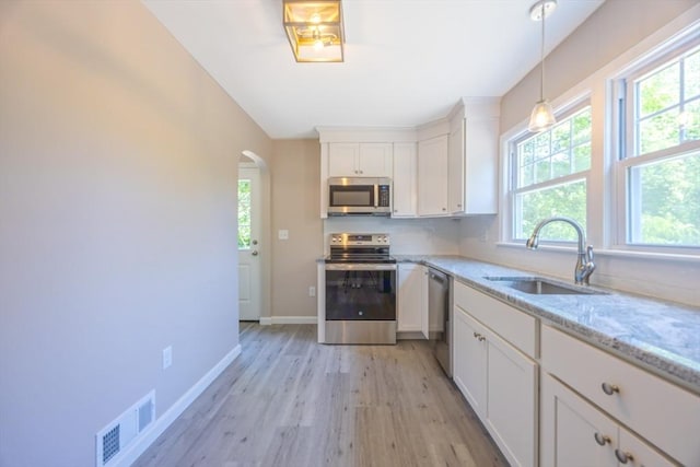 136 E St, South Hadley, MA 01075 - kitchen featuring stainless steel appliances, light wood-type flooring, arched walkways, white cabinets, and light stone countertops
