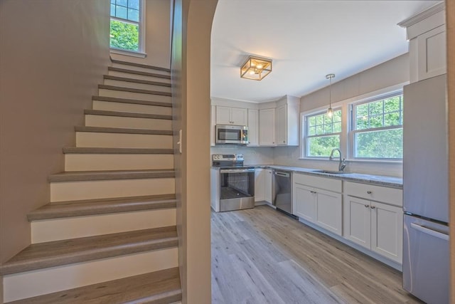 136 E St, South Hadley, MA 01075 - kitchen featuring appliances with stainless steel finishes, light wood-type flooring, white cabinetry, decorative light fixtures, and decorative backsplash