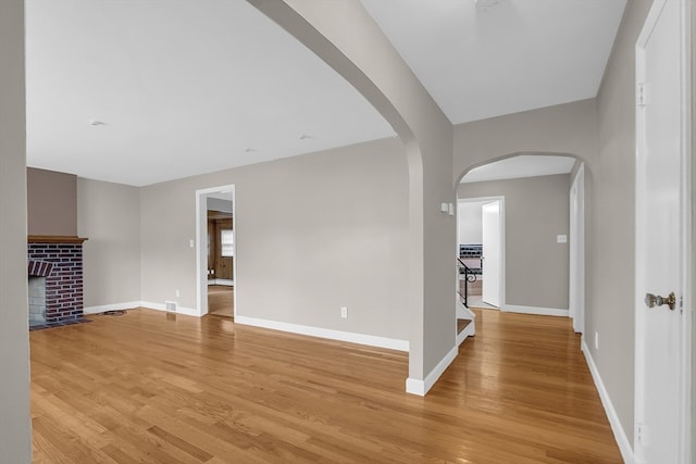 unfurnished living room with light hardwood / wood-style flooring and a brick fireplace