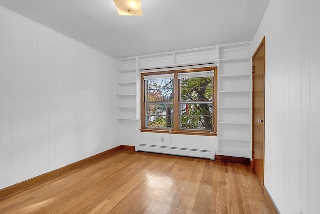 unfurnished room featuring baseboard heating and light hardwood / wood-style flooring