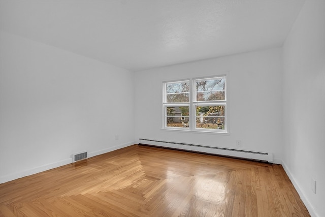 unfurnished room featuring baseboard heating and light parquet flooring