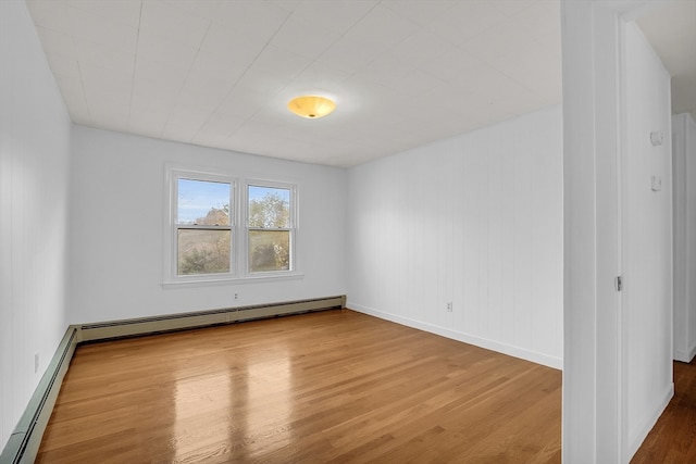 unfurnished room featuring hardwood / wood-style flooring and a baseboard heating unit