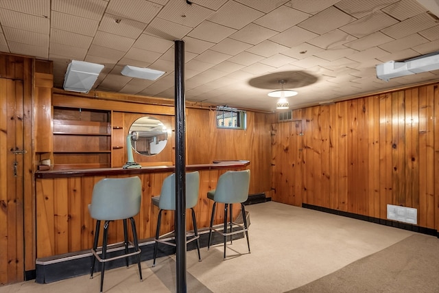 bar featuring light carpet and wooden walls