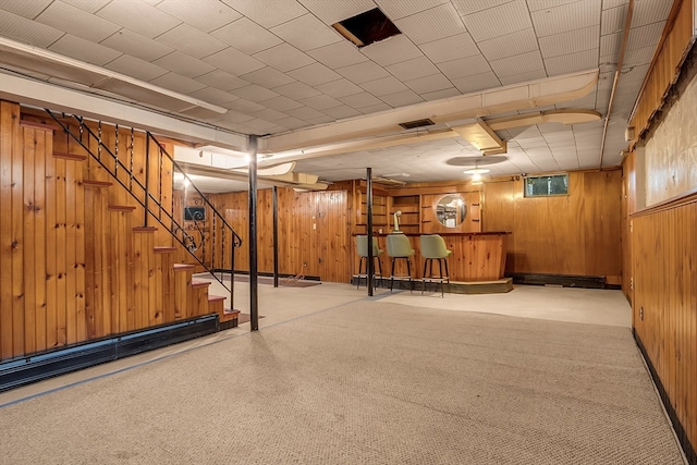 basement featuring bar and wooden walls