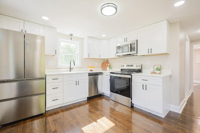 kitchen with stainless steel appliances, a sink, dark wood-style flooring, light countertops, and white cabinets