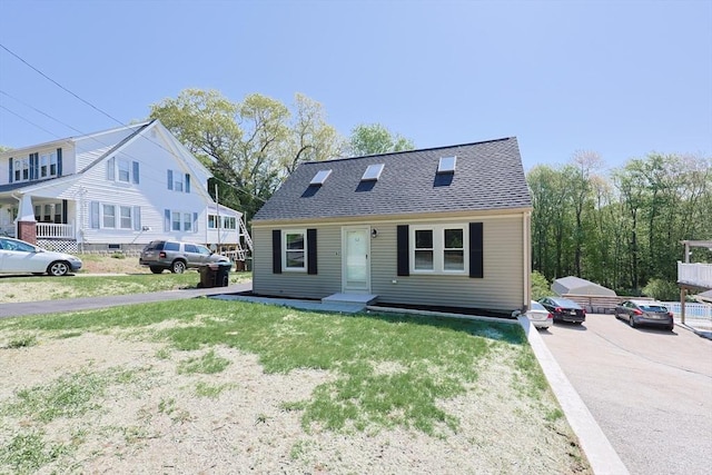 view of front of house with a front lawn and roof with shingles