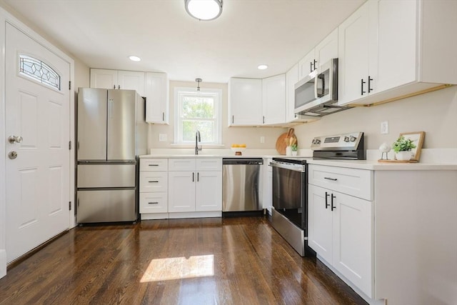 kitchen with stainless steel appliances, dark wood finished floors, white cabinets, light countertops, and recessed lighting
